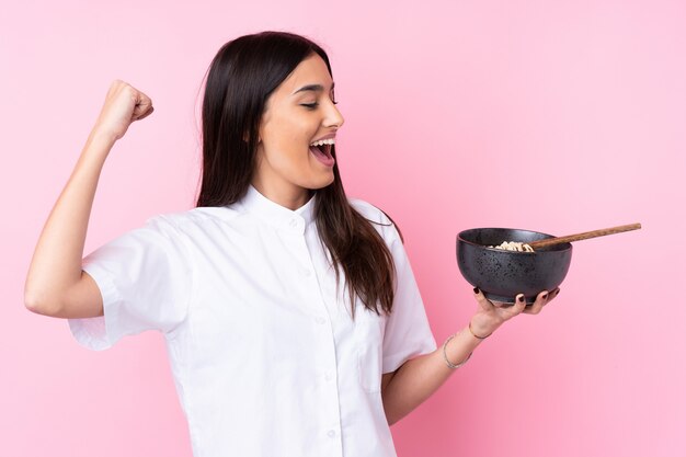 Jeune femme brune sur rose célébrant une victoire