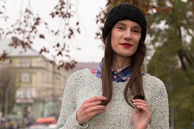 Jeune femme brune souriante dans un pull chaud et une casquette