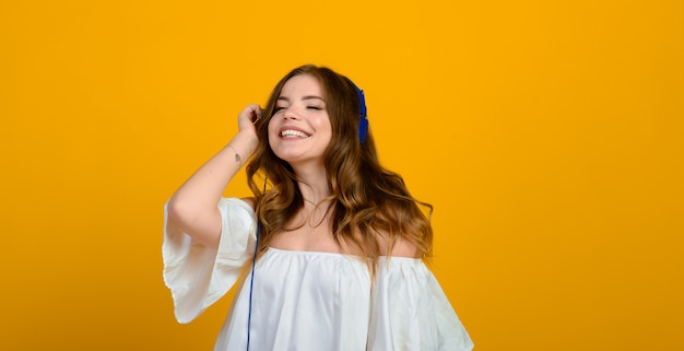 Jeune femme brune avec un sourire et de grands yeux surpris posant.