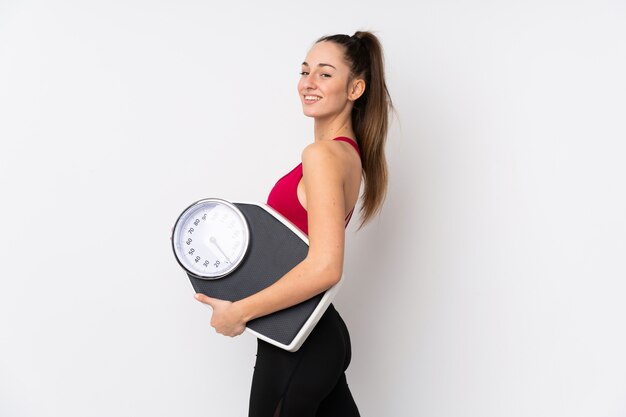 Jeune femme brune sport sur mur blanc isolé avec machine de pesage