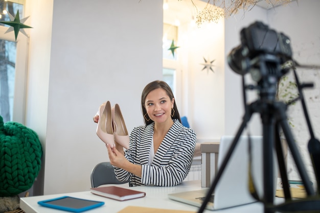 Jeune femme brune en streaming une vidéo tout en présentant de très belles chaussures pour un cadeau