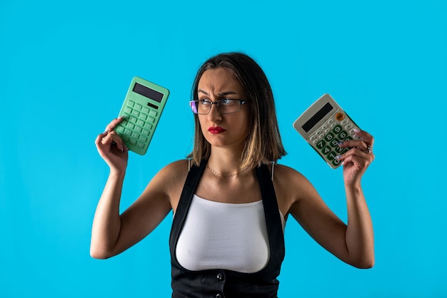 Jeune femme brune tenant une calculatrice criant portant des lunettes isolées sur fond bleu