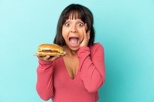 Jeune femme brune tenant un hamburger sur une surface isolée