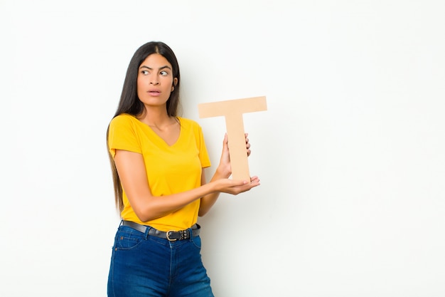 jeune femme brune tenant la lettre T de l'alphabet pour former un mot ou une phrase