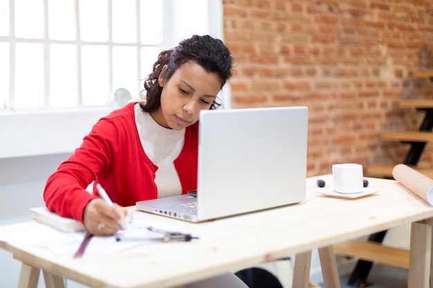 Jeune femme brune travaillant dur depuis son bureau à domicile. Espace pour le texte. Concept de plans et de nouveaux projets.