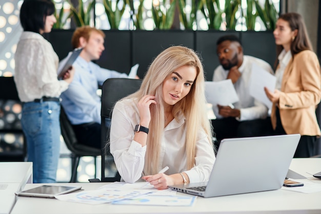 Jeune femme de bureau très ciblée, saisie de données du rapport financier à l'ordinateur portable dans le bureau moderne