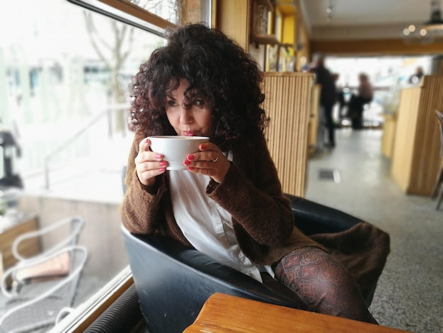 Une jeune femme buvant dans un café.