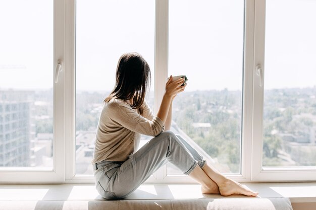 Jeune femme buvant du café à la maison