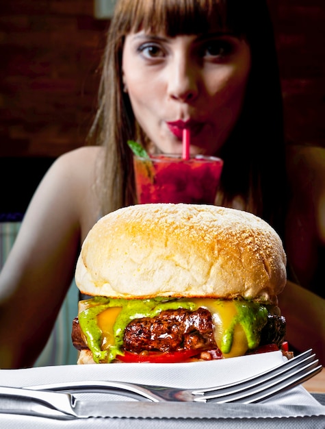 Photo jeune femme buvant du jus de manger un hamburger