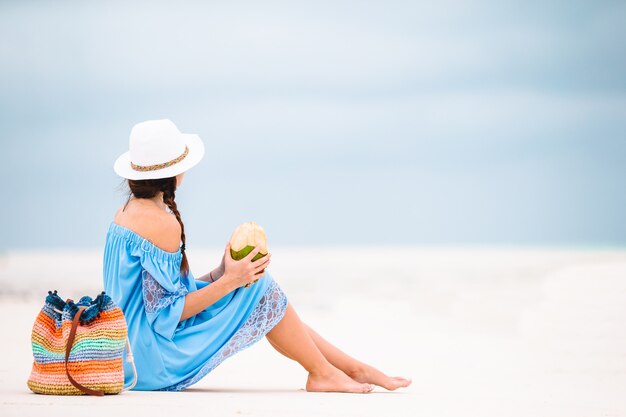 Jeune femme buvant du lait de coco pendant les vacances tropicales