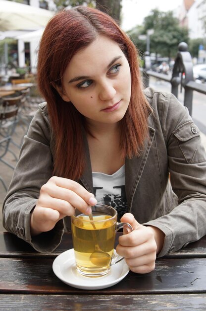 jeune femme buvant du thé dans un café de rue