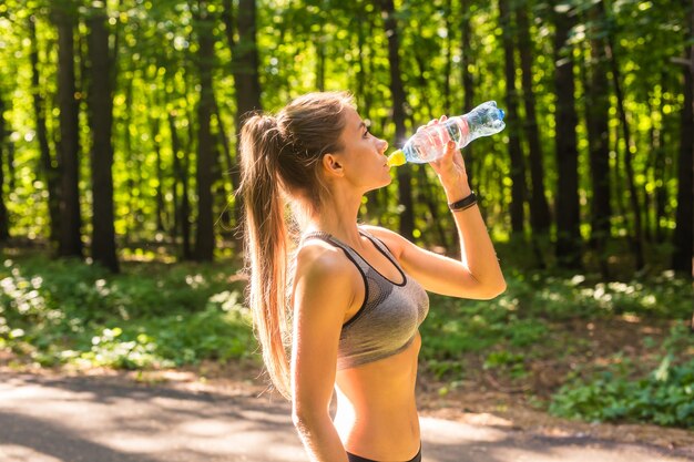 Jeune femme buvant de l'eau après avoir couru à l'extérieur.