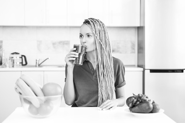 Jeune femme buvant un smoothie vert dans la cuisine avec des fruits et légumes une alimentation saine lifesty