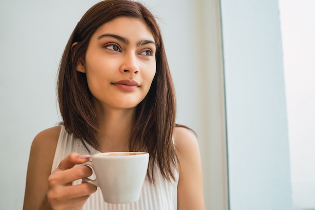 Jeune femme buvant une tasse de café au café.