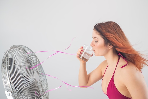 Une jeune femme buvant un verre sur un fond blanc