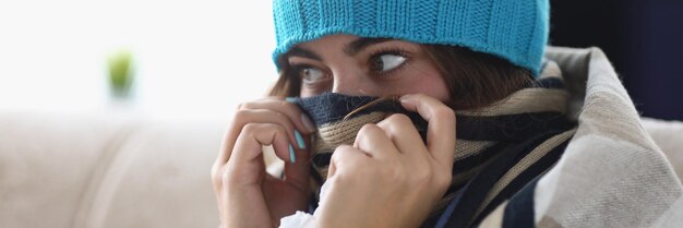 Jeune femme cacher le nez dans l'écharpe sensation de froid à cause de la température élevée