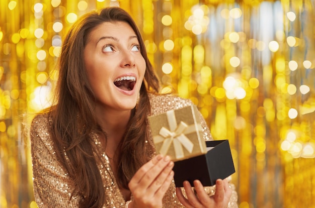 Jeune femme avec un cadeau sur fond d'or