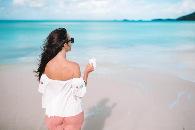 Jeune femme avec café chaud en profitant de la vue sur la plage