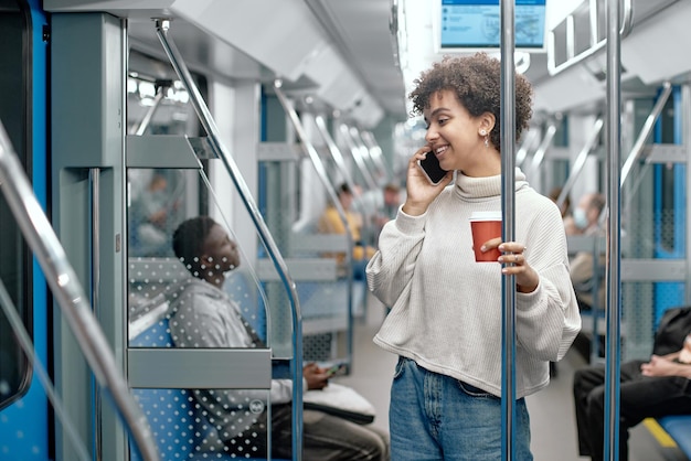 Jeune femme avec un café à emporter parlant sur un smartphone dans un