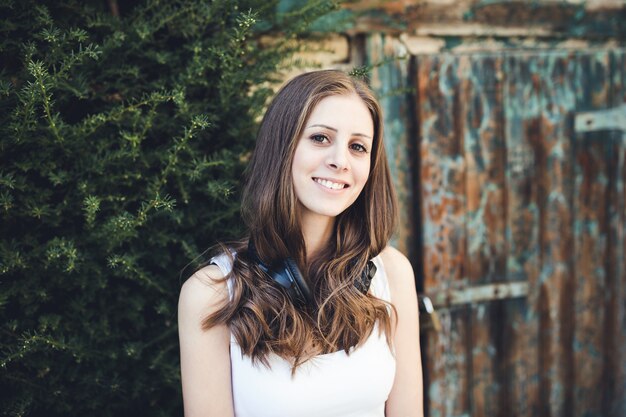 Jeune femme à la campagne avec des écouteurs à l'extérieur, souriant