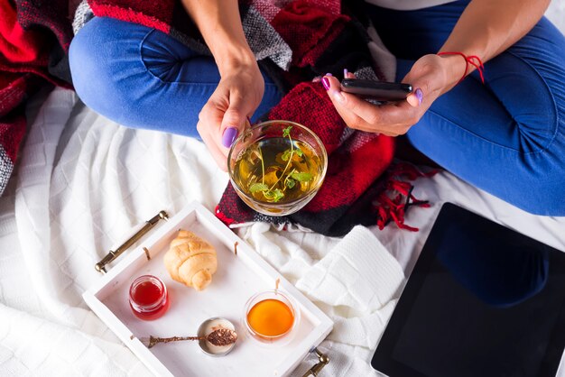 La jeune femme sur le canapé et avec du thé à la sauge sur la main.