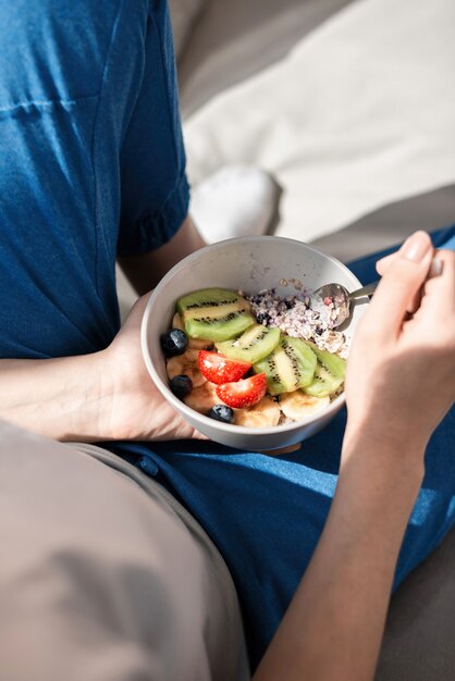 Jeune femme sur un canapé avec salade de bouillie, vue de dessus