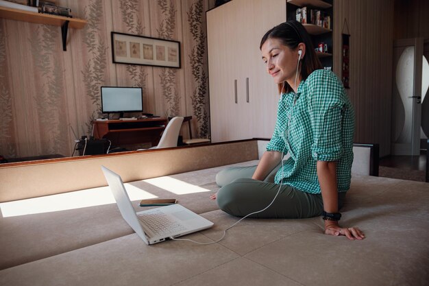 Jeune femme sur un canapé travaillant joyeusement sur un nouveau projet avec un ordinateur portable à la maison