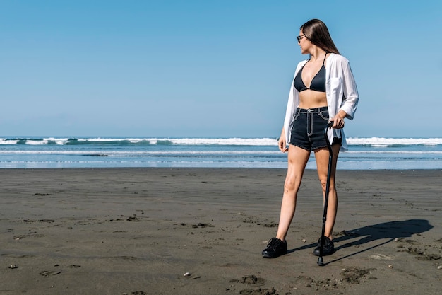 Jeune femme avec canne regardant la mer