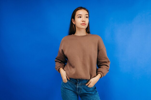 Jeune femme à capuche qui pose en studio sur fond bleu