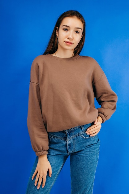 Jeune femme à capuche qui pose en studio sur fond bleu