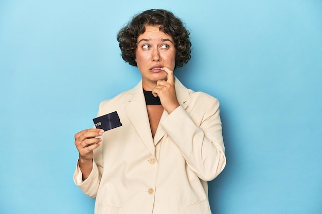 Photo jeune femme avec carte de crédit élégant blazer blanc détendu en pensant à quelque chose