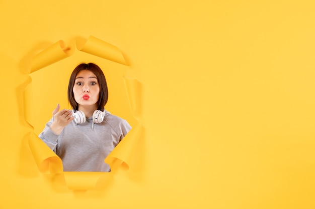 jeune femme avec un casque sur fond de papier jaune audio