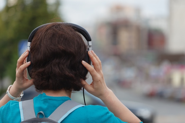 Jeune femme avec un casque, profitant du temps dans une ville.