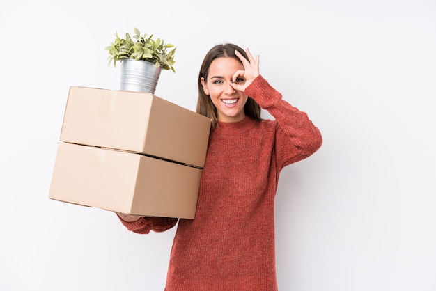 Jeune femme caucasic tenant des boîtes isolées excité en gardant le geste correct sur l'oeil.