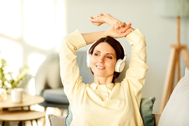 Jeune femme caucasienne adulte portant des vêtements décontractés se relaxant dans le salon à la maison écoutant de la musique