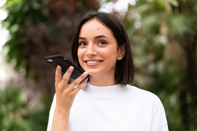 Jeune femme caucasienne à l'aide d'un téléphone à l'extérieur