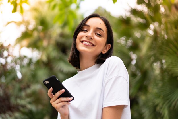 Jeune femme caucasienne à l'aide d'un téléphone à l'extérieur