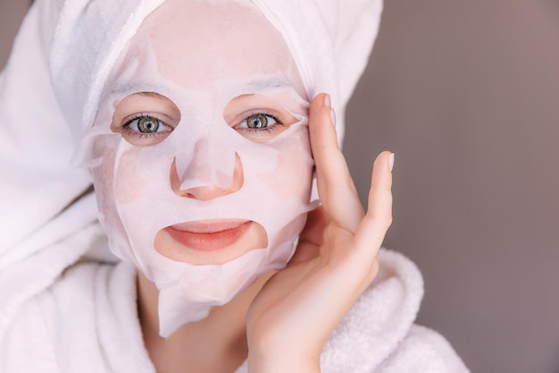 Jeune femme caucasienne appliquant un masque facial portant un peignoir et