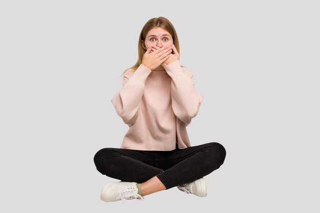 Jeune femme caucasienne assise sur la découpe du sol isolée