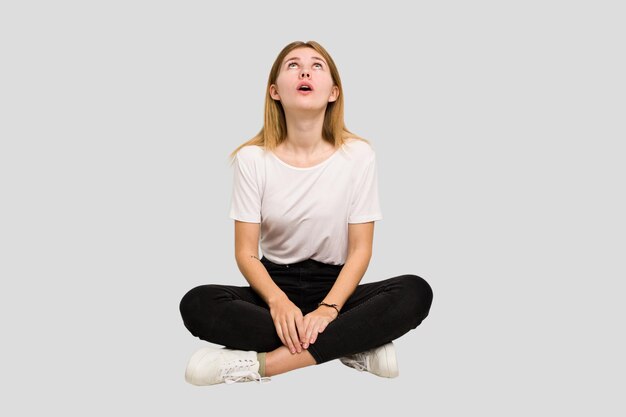 Jeune femme caucasienne assise sur la découpe du sol isolée