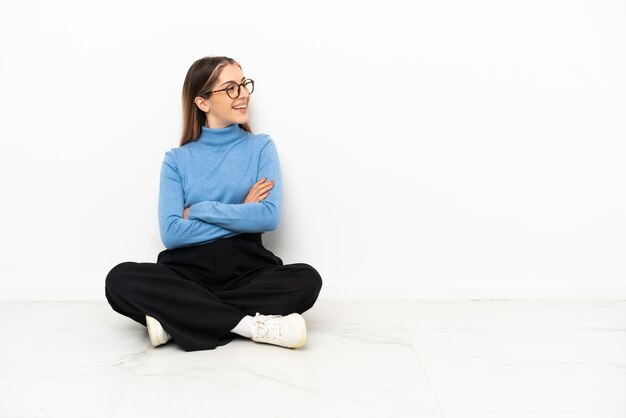 Jeune femme caucasienne assise sur le sol heureuse et souriante