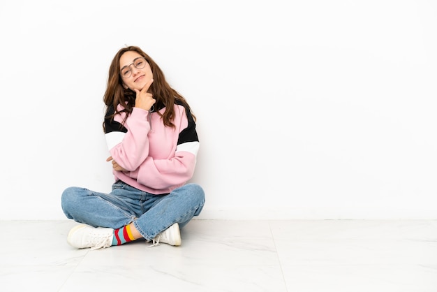 Photo jeune femme caucasienne assise sur le sol isolé sur fond blanc souriant