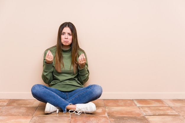 Jeune femme caucasienne assise sur le sol isolé montrant qu'elle n'a pas d'argent.