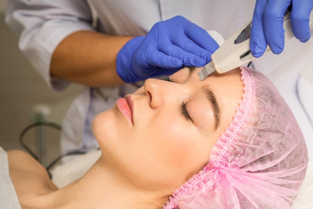 Jeune femme caucasienne ayant un peeling ultrasonique avec un appareil à ultrasons dans un salon de beauté cosmétique.