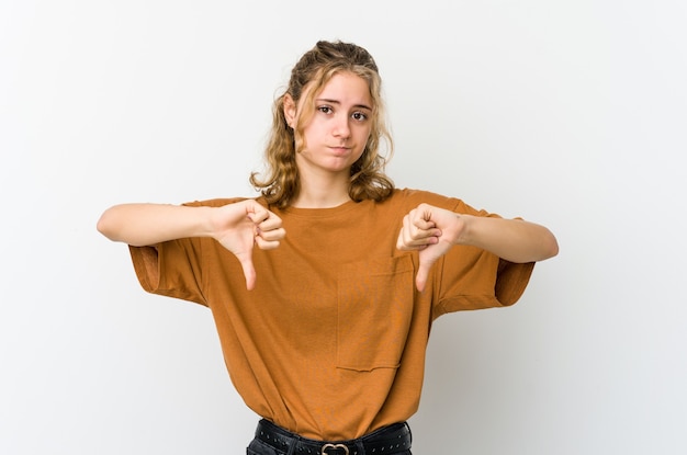 Jeune femme caucasienne sur blanc montrant le pouce vers le bas, concept de déception.