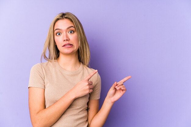 Jeune femme caucasienne blonde isolée choquée pointant avec l'index vers un espace de copie.