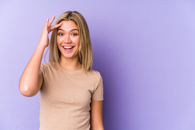 Jeune femme caucasienne blonde isolée crie fort, garde les yeux ouverts et les mains tendues.