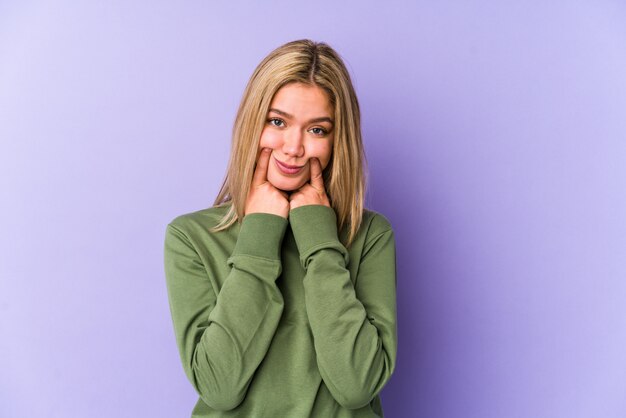 Jeune femme caucasienne blonde isolée doutant entre deux options.