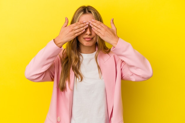 Jeune femme caucasienne blonde isolée sur fond jaune peur couvrant les yeux avec les mains.