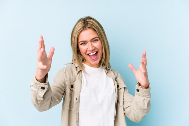 Jeune femme caucasienne blonde isolée recevant une agréable surprise, excitée et levant les mains.